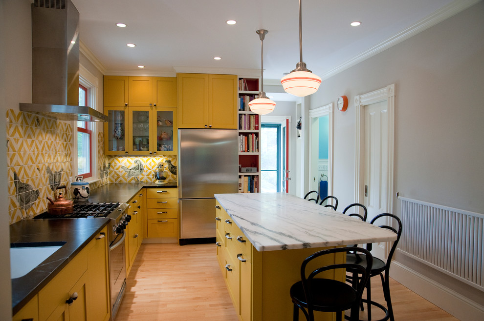 На фото: угловая, отдельная кухня среднего размера в стиле фьюжн с врезной мойкой, фасадами в стиле шейкер, желтыми фасадами, столешницей из талькохлорита, фартуком из керамической плитки и техникой из нержавеющей стали с