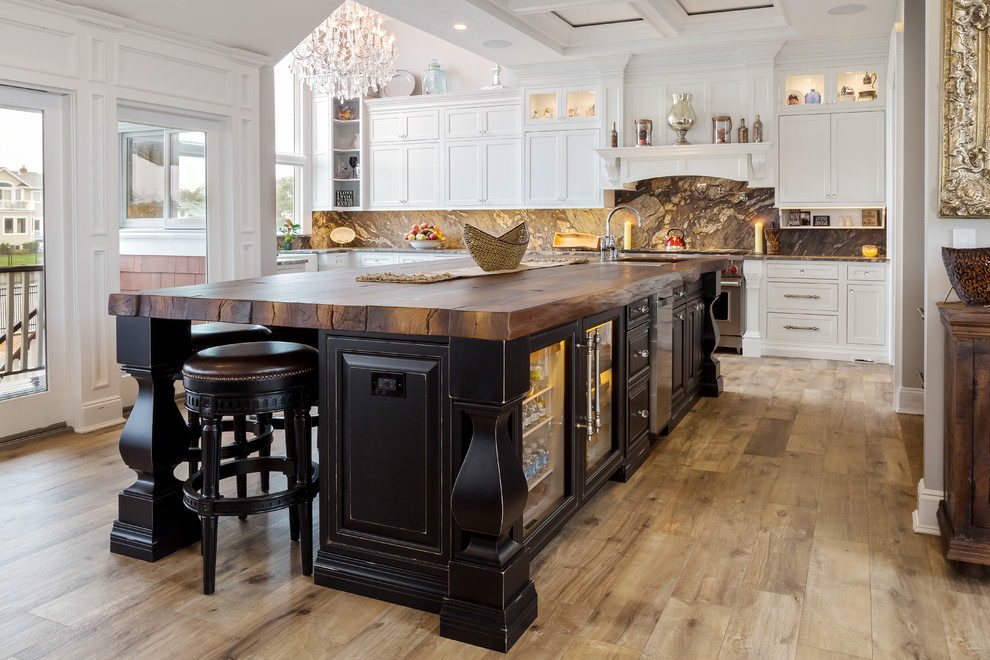 Inspiration for an expansive rustic l-shaped kitchen/diner in New York with beaded cabinets, porcelain flooring, an island, brown splashback, a belfast sink, white cabinets, granite worktops, stone slab splashback and stainless steel appliances.