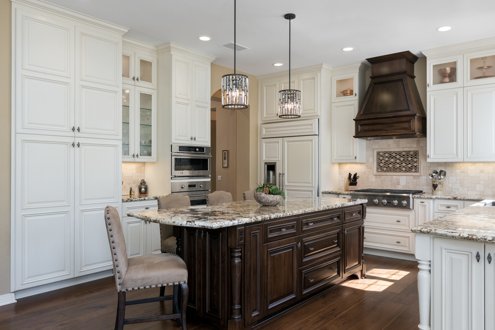 Example of a large classic u-shaped medium tone wood floor and brown floor eat-in kitchen design in San Diego with an undermount sink, raised-panel cabinets, white cabinets, quartz countertops, beige backsplash, stone tile backsplash, stainless steel appliances, an island and multicolored countertops