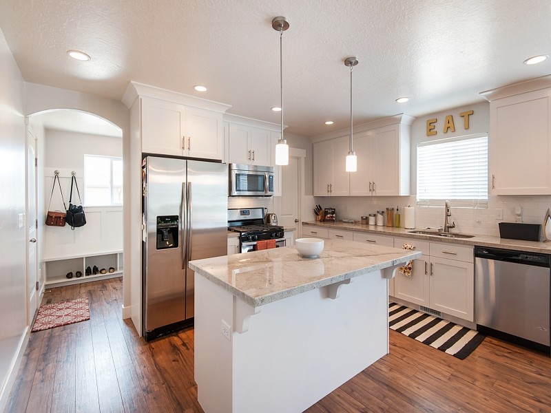 Inspiration for a large craftsman l-shaped medium tone wood floor eat-in kitchen remodel in Salt Lake City with recessed-panel cabinets, white cabinets, quartzite countertops, white backsplash, subway tile backsplash, stainless steel appliances and an island