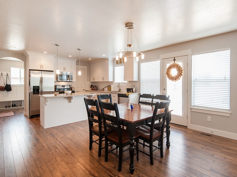 Large arts and crafts l-shaped medium tone wood floor eat-in kitchen photo in Salt Lake City with recessed-panel cabinets, white cabinets, quartzite countertops, white backsplash, subway tile backsplash, stainless steel appliances and an island