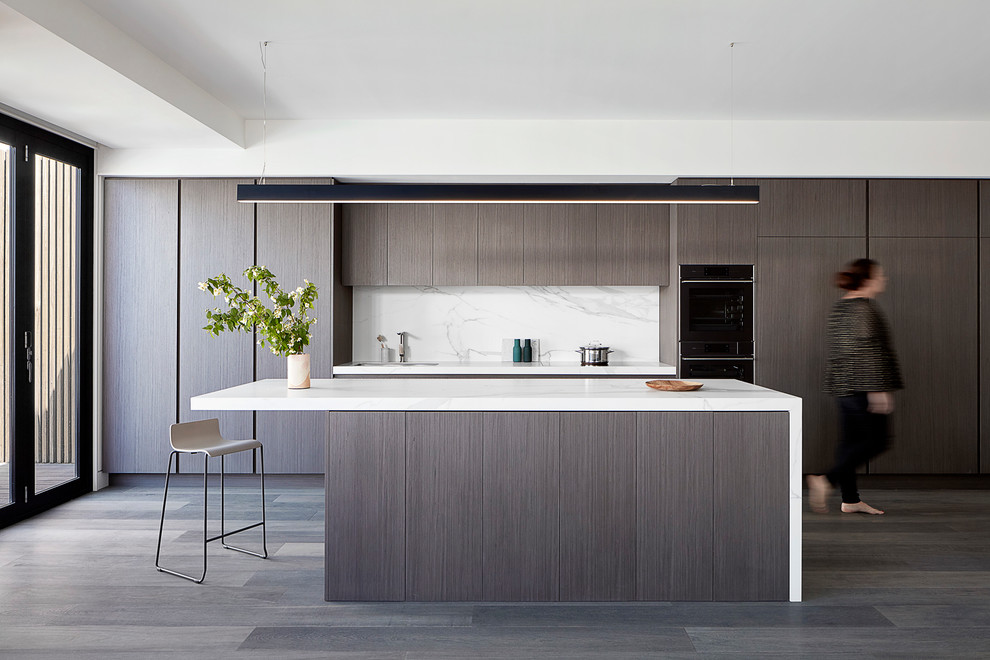 Small contemporary single-wall open plan kitchen in Melbourne with flat-panel cabinets, dark wood cabinets, white splashback, stone slab splashback, dark hardwood flooring, an island and brown floors.