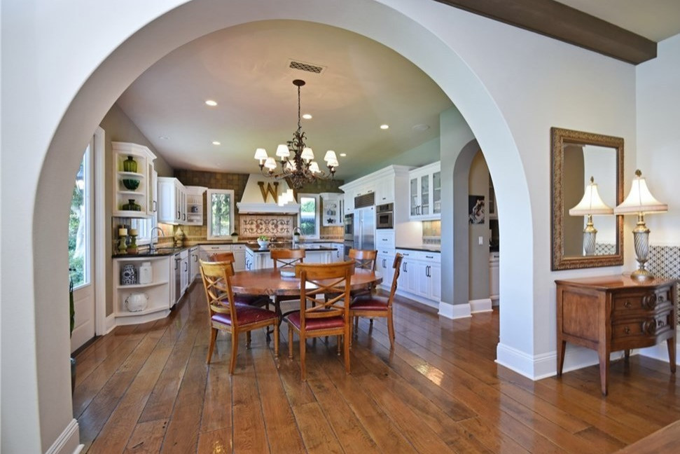 Exempel på ett stort medelhavsstil grön grönt kök, med en undermonterad diskho, luckor med glaspanel, vita skåp, granitbänkskiva, grått stänkskydd, stänkskydd i skiffer, rostfria vitvaror, mellanmörkt trägolv, en köksö och brunt golv