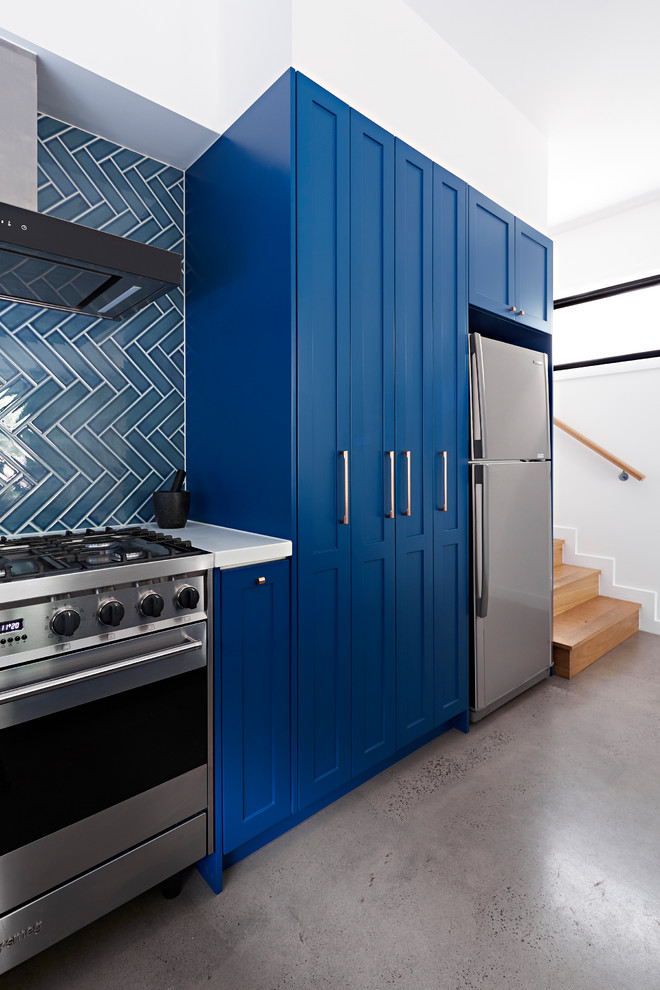 メルボルンにある中くらいなトランジショナルスタイルのおしゃれなキッチン (ダブルシンク、シェーカースタイル扉のキャビネット、青いキャビネット、青いキッチンパネル、セラミックタイルのキッチンパネル、シルバーの調理設備、コンクリートの床、グレーの床、白いキッチンカウンター、クオーツストーンカウンター) の写真