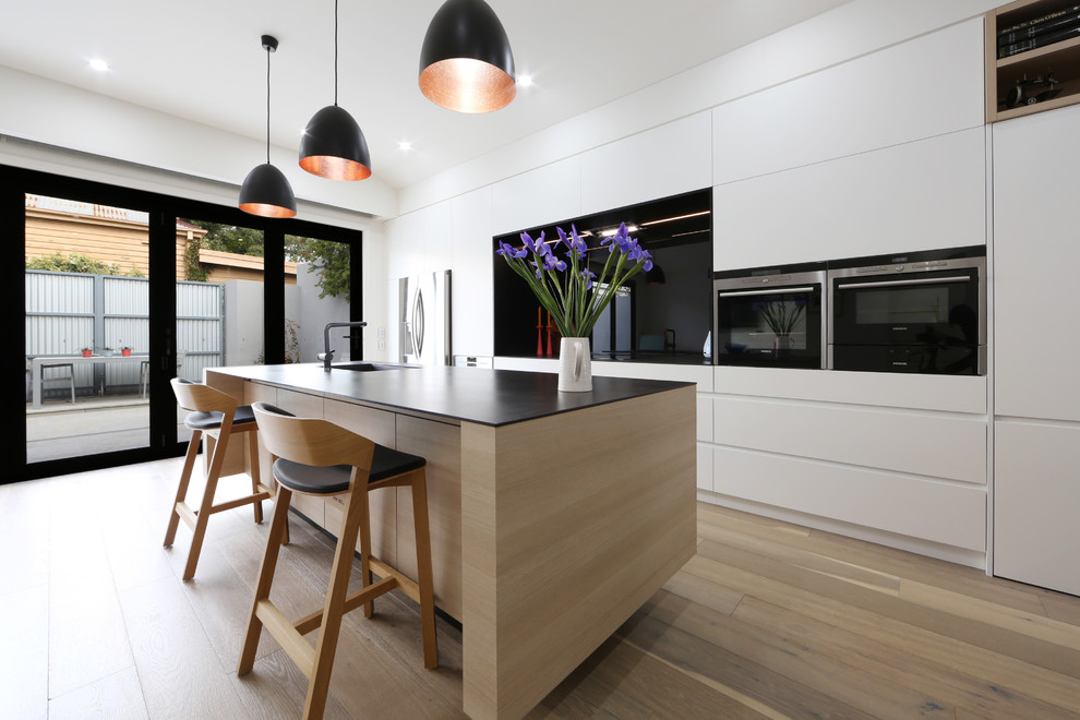 Ispirazione per una cucina scandinava con ante lisce, ante bianche, paraspruzzi nero e pavimento in legno massello medio