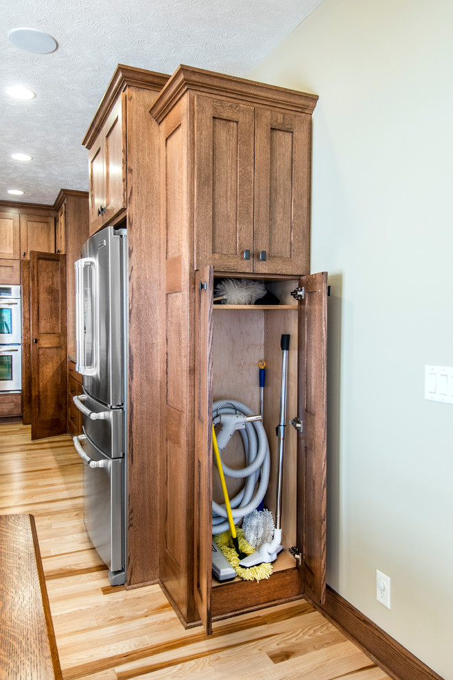 Example of a mid-sized arts and crafts l-shaped medium tone wood floor eat-in kitchen design in Omaha with a single-bowl sink, shaker cabinets, medium tone wood cabinets, granite countertops, stainless steel appliances and an island