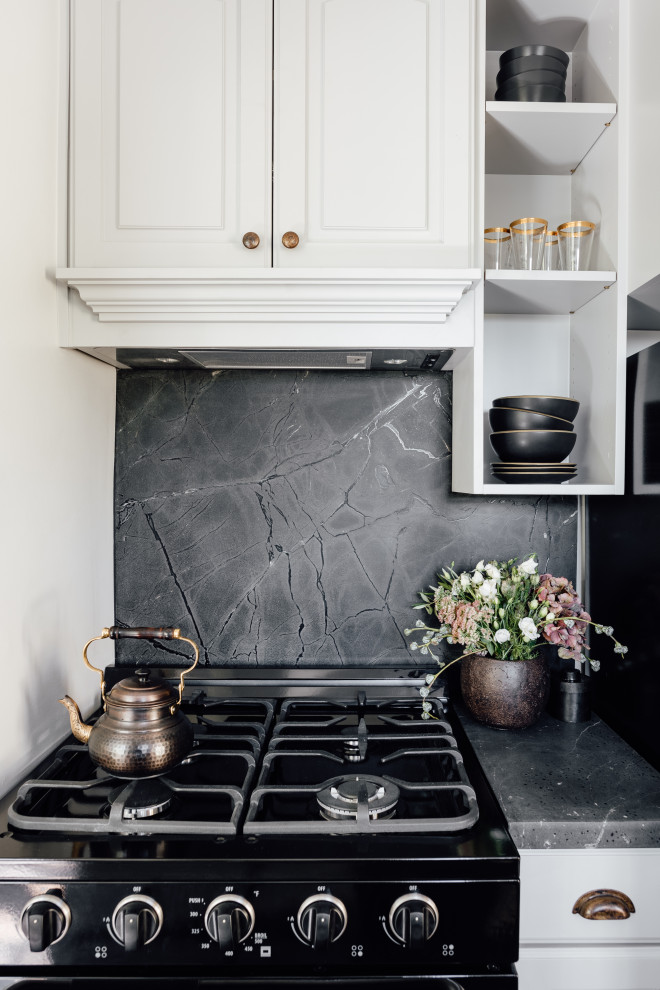Cette image montre une petite cuisine traditionnelle en L fermée avec un placard à porte shaker, des portes de placard grises, une crédence noire, une crédence en marbre, un électroménager noir et plan de travail noir.