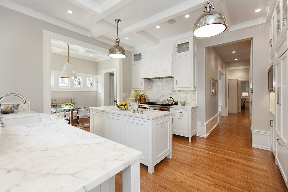 This is an example of an expansive traditional galley enclosed kitchen in San Francisco with a single-bowl sink, shaker cabinets, white cabinets, white splashback, stainless steel appliances, medium hardwood flooring, an island, marble worktops, marble splashback and beige floors.