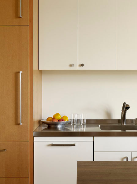 Cette image montre une cuisine linéaire et encastrable design avec un placard à porte plane, un plan de travail en bois, une crédence blanche et un évier intégré.