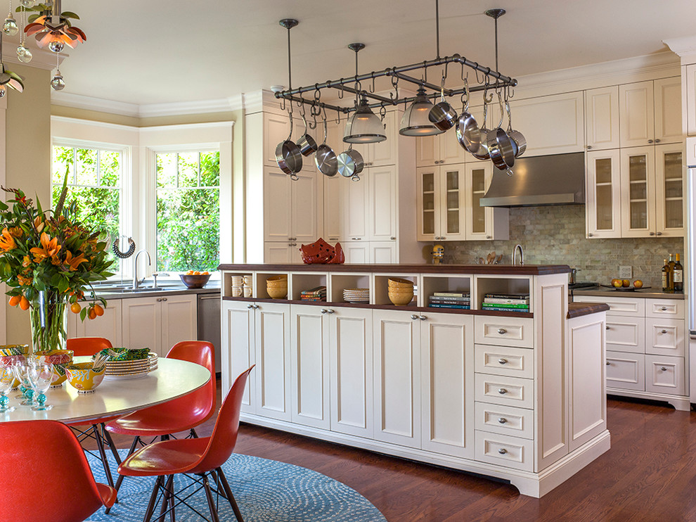 Eat-in kitchen - mid-sized transitional l-shaped medium tone wood floor eat-in kitchen idea in San Francisco with white cabinets, stainless steel countertops, green backsplash, stone tile backsplash and paneled appliances