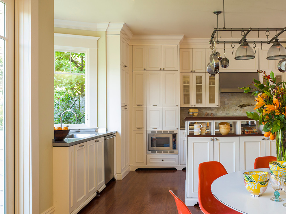 サンフランシスコにある高級な中くらいなトランジショナルスタイルのおしゃれなキッチン (落し込みパネル扉のキャビネット、白いキャビネット、ステンレスカウンター、緑のキッチンパネル、パネルと同色の調理設備、無垢フローリング) の写真