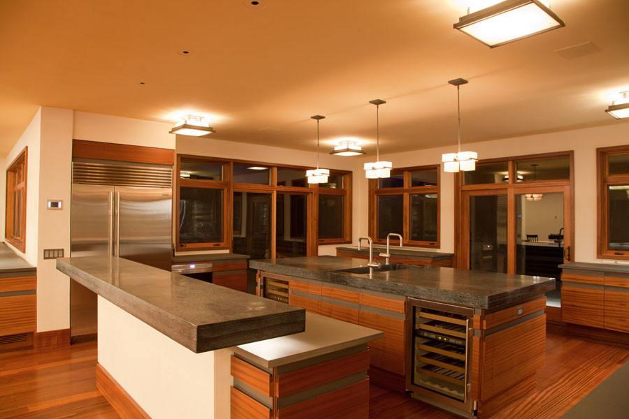 Foto di una grande cucina minimal con lavello sottopiano, ante lisce, ante in legno scuro, top in granito, elettrodomestici in acciaio inossidabile, pavimento in legno massello medio e 2 o più isole