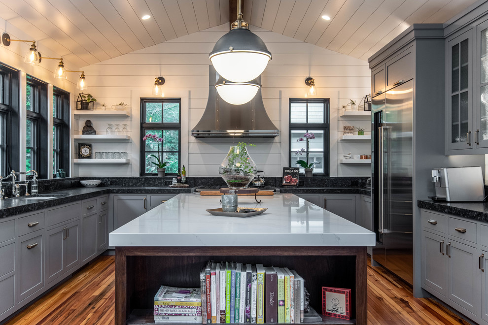 Design ideas for a large coastal grey and black u-shaped kitchen in Other with grey cabinets, stainless steel appliances, medium hardwood flooring, an island, a submerged sink, shaker cabinets and black worktops.