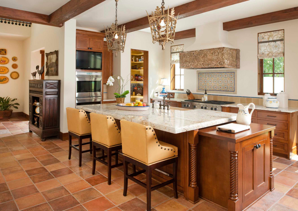 Foto på ett medelhavsstil flerfärgad l-kök, med skåp i mellenmörkt trä, flerfärgad stänkskydd, rostfria vitvaror, klinkergolv i terrakotta, en köksö och orange golv