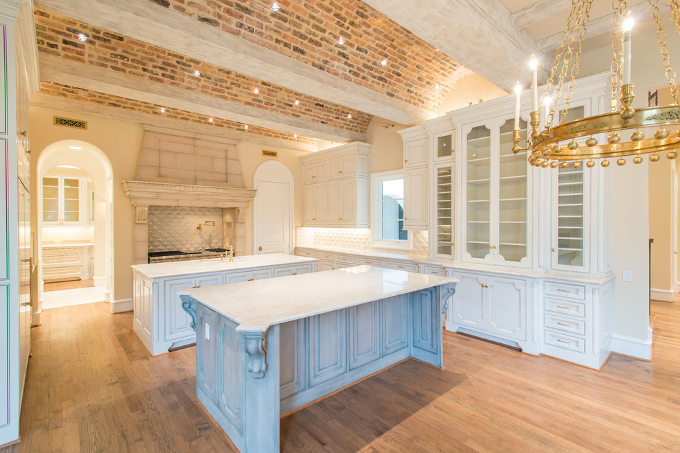 Inspiration for a large mediterranean u-shaped medium tone wood floor open concept kitchen remodel in Dallas with quartzite countertops, white backsplash, two islands, recessed-panel cabinets and white cabinets