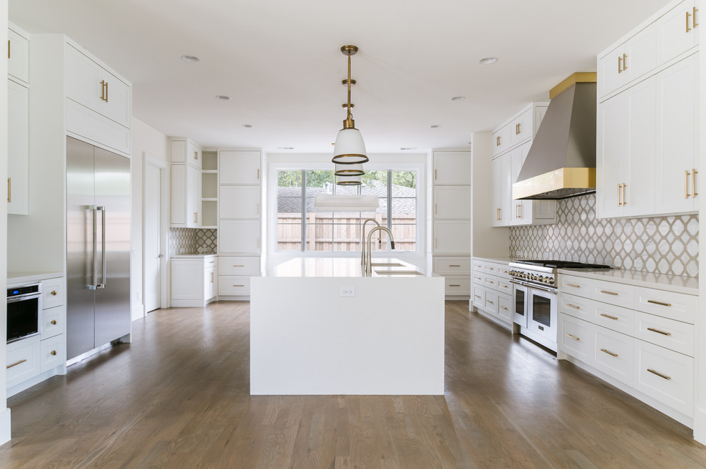 Klassisk inredning av ett mycket stort kök, med en undermonterad diskho, skåp i shakerstil, vita skåp, bänkskiva i kvarts, vitt stänkskydd, stänkskydd i marmor, rostfria vitvaror, mellanmörkt trägolv, en köksö och brunt golv