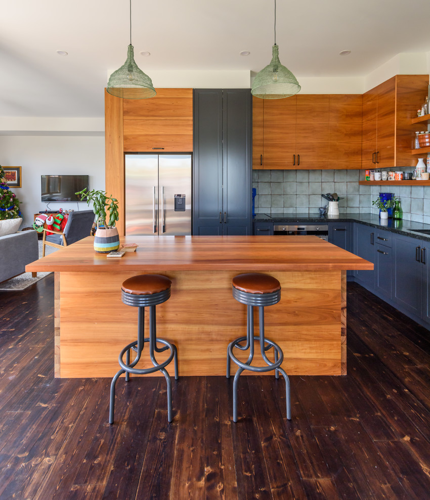 This is an example of a traditional l-shaped open plan kitchen in Melbourne with a submerged sink, flat-panel cabinets, medium wood cabinets, wood worktops, black splashback, dark hardwood flooring, an island and brown floors.
