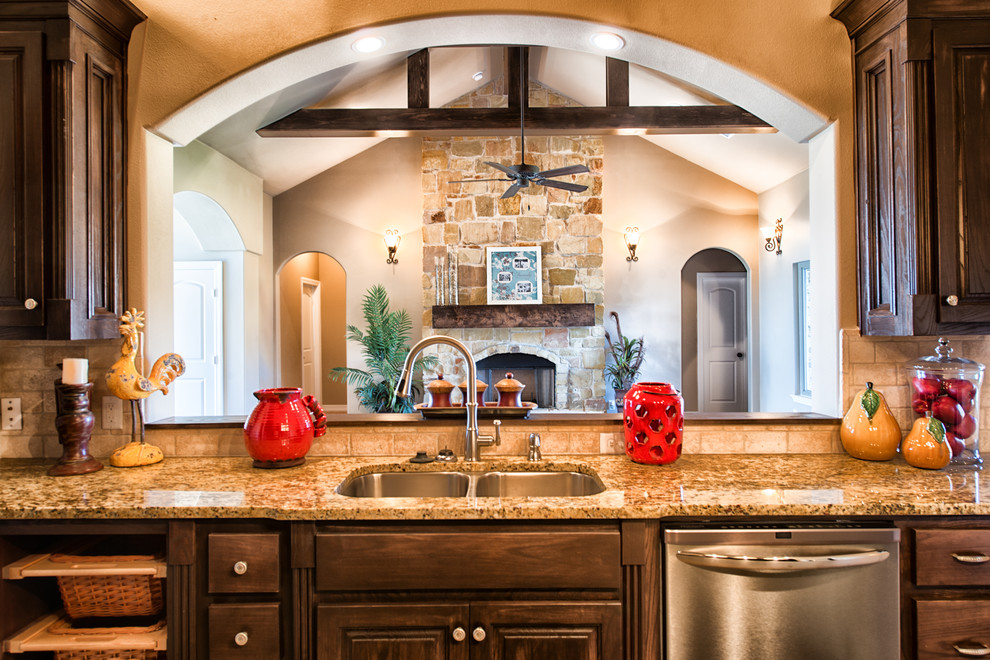 Inspiration for a large timeless u-shaped ceramic tile eat-in kitchen remodel in Dallas with an undermount sink, dark wood cabinets, granite countertops, beige backsplash, stone tile backsplash and stainless steel appliances