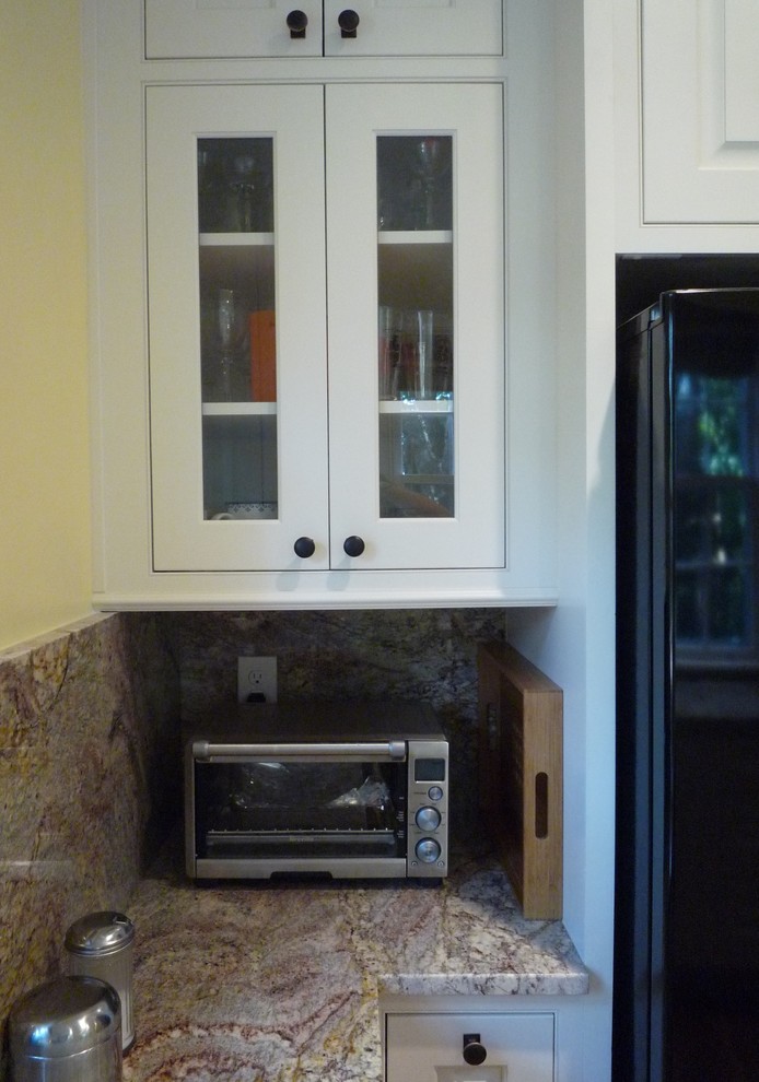 Foto på ett avskilt, mellanstort vintage kök, med en undermonterad diskho, luckor med upphöjd panel, vita skåp, granitbänkskiva, flerfärgad stänkskydd, stänkskydd i sten, rostfria vitvaror och mellanmörkt trägolv