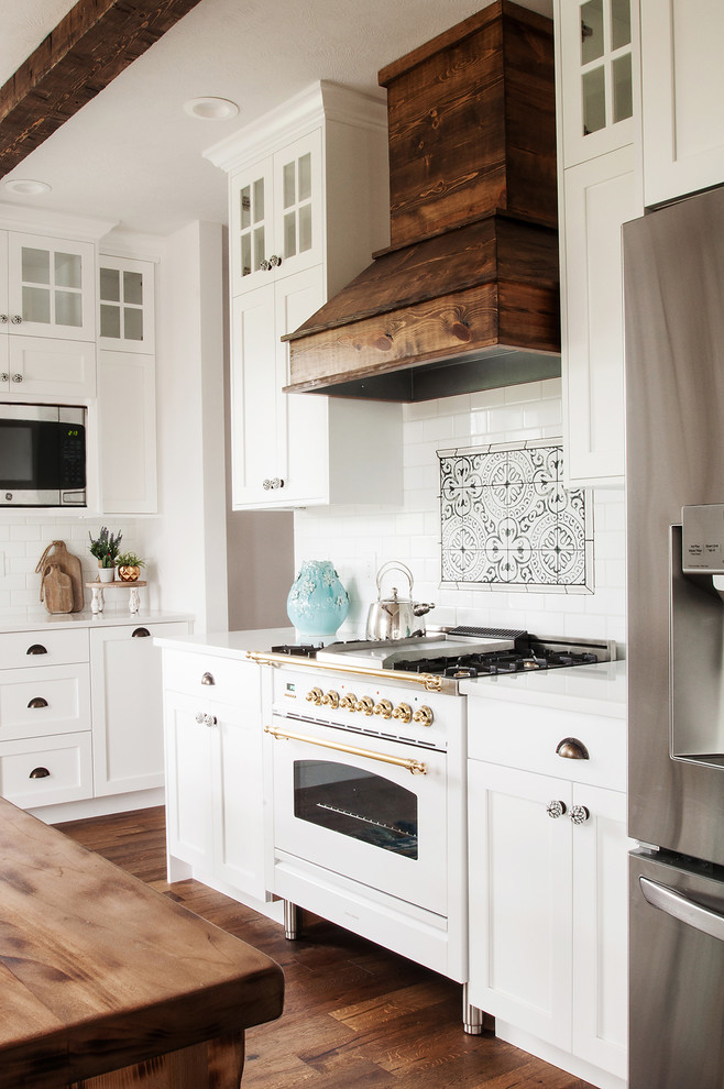 Inspiration for a large country l-shaped kitchen in Indianapolis with shaker cabinets, white cabinets, engineered stone countertops, white splashback, ceramic splashback, stainless steel appliances, medium hardwood flooring and white worktops.