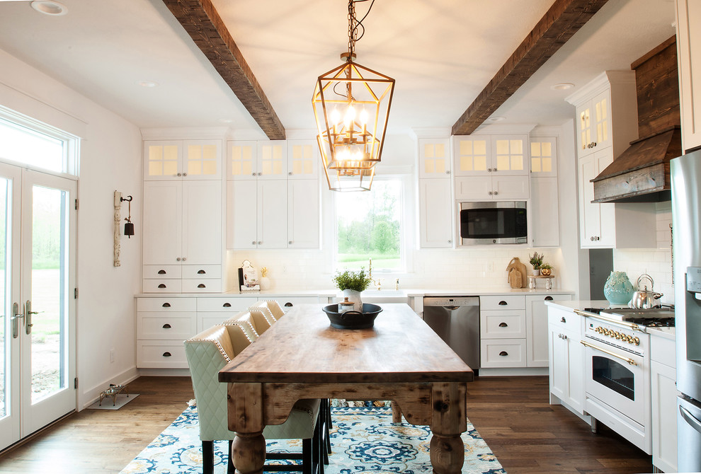 Photo of a large rural l-shaped kitchen in Indianapolis with shaker cabinets, white cabinets, engineered stone countertops, white splashback, ceramic splashback, stainless steel appliances, medium hardwood flooring and white worktops.