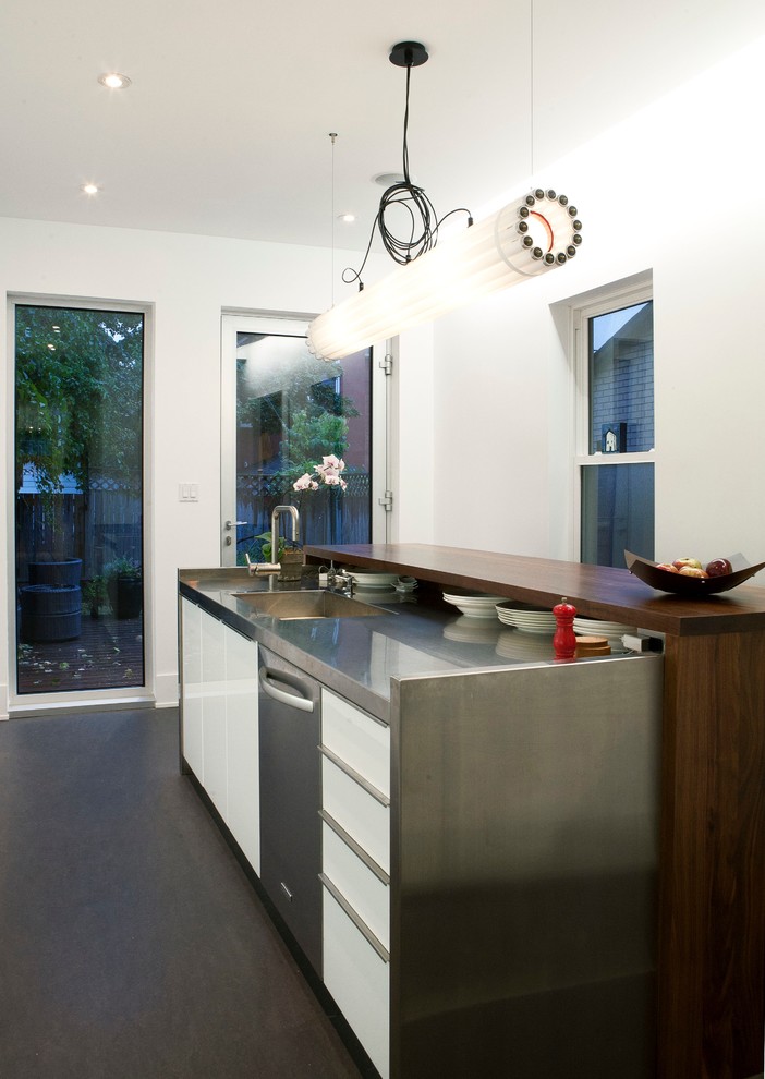 На фото: кухня в стиле модернизм с плоскими фасадами, белыми фасадами и столешницей из нержавеющей стали с