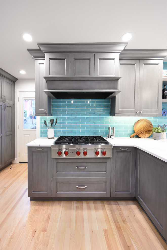 Design ideas for a large classic kitchen/diner in Seattle with a belfast sink, recessed-panel cabinets, grey cabinets, engineered stone countertops, blue splashback, ceramic splashback, stainless steel appliances, light hardwood flooring, a breakfast bar, yellow floors and white worktops.