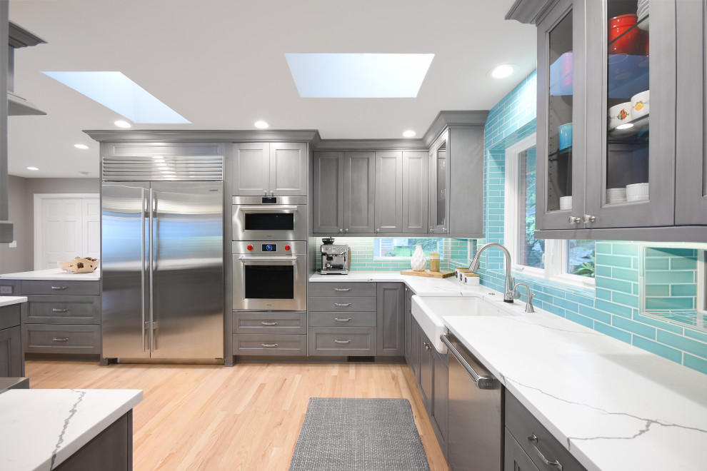Inspiration for a large transitional light wood floor and yellow floor eat-in kitchen remodel in Seattle with a farmhouse sink, recessed-panel cabinets, gray cabinets, quartz countertops, blue backsplash, ceramic backsplash, stainless steel appliances, a peninsula and white countertops