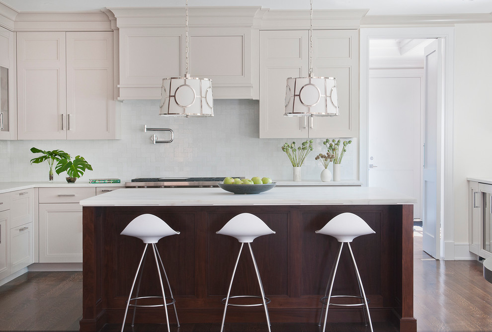 Klassische Küche mit Schrankfronten mit vertiefter Füllung, beigen Schränken, Küchenrückwand in Weiß, Küchengeräten aus Edelstahl, braunem Holzboden und Kücheninsel in New York