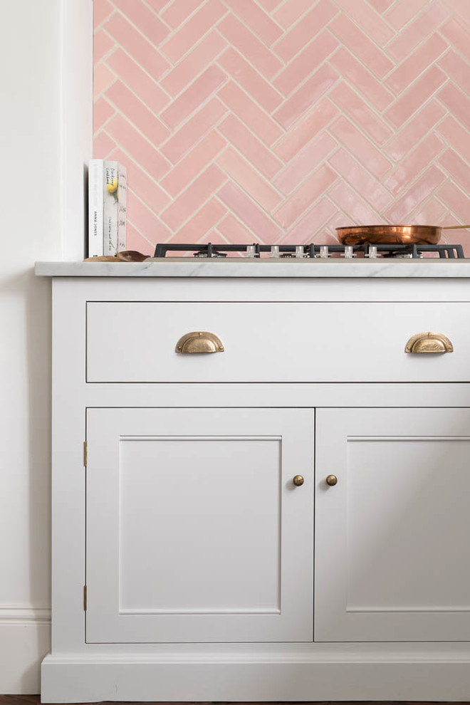 Inspiration pour une cuisine américaine avec un placard à porte shaker, des portes de placard blanches, plan de travail en marbre, une crédence rose, une crédence en céramique et un plan de travail blanc.