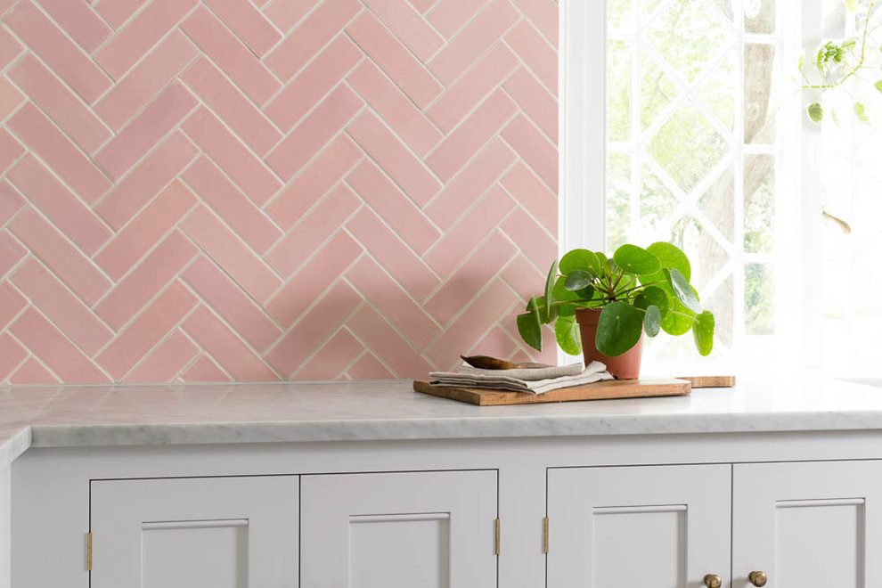 Exemple d'une cuisine américaine avec un placard à porte shaker, des portes de placard blanches, plan de travail en marbre, une crédence rose, une crédence en céramique et un plan de travail blanc.