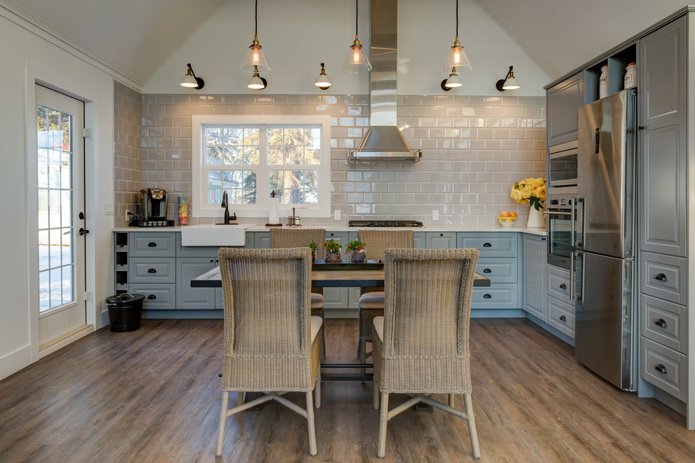 Bild på ett litet lantligt kök, med en rustik diskho, luckor med upphöjd panel, grå skåp, bänkskiva i kvarts, grått stänkskydd, stänkskydd i porslinskakel, rostfria vitvaror och vinylgolv