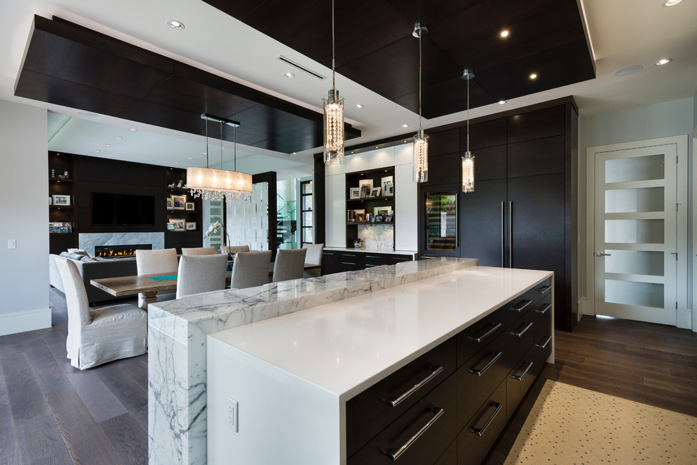 Example of a large trendy l-shaped medium tone wood floor and brown floor open concept kitchen design in Vancouver with an undermount sink, flat-panel cabinets, marble countertops, white backsplash, marble backsplash, stainless steel appliances and an island