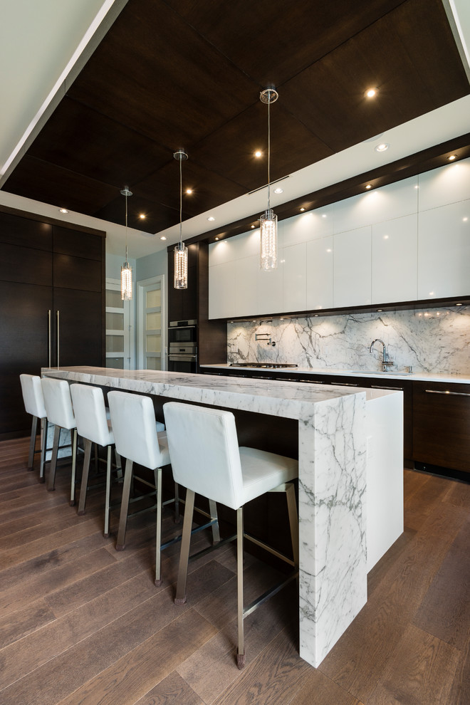 Inspiration for a large contemporary l-shaped medium tone wood floor and brown floor open concept kitchen remodel in Vancouver with an undermount sink, flat-panel cabinets, marble countertops, white backsplash, marble backsplash, stainless steel appliances and an island