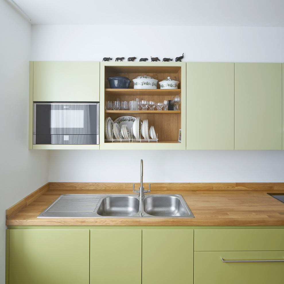 Einzeilige, Mittelgroße Moderne Küche ohne Insel mit Doppelwaschbecken, flächenbündigen Schrankfronten, grünen Schränken und Arbeitsplatte aus Holz in London