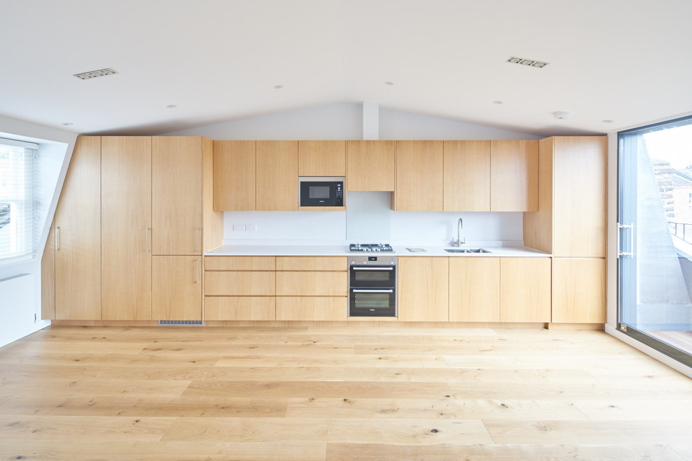 Photo of a medium sized modern single-wall kitchen in London with an integrated sink, flat-panel cabinets, light wood cabinets, composite countertops, light hardwood flooring and no island.