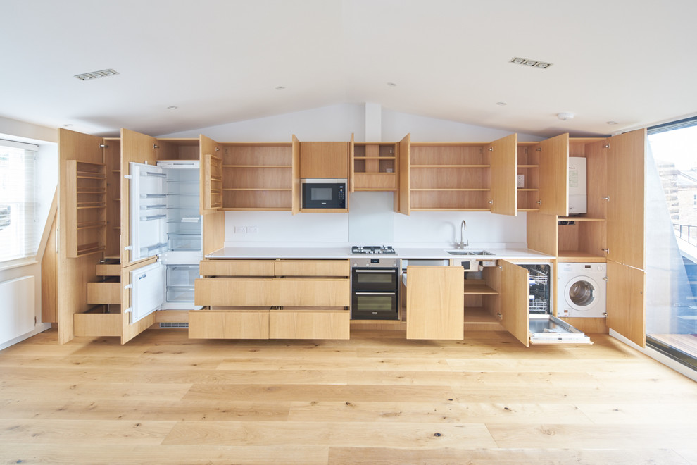 Einzeilige, Mittelgroße Moderne Küche ohne Insel mit integriertem Waschbecken, flächenbündigen Schrankfronten, hellen Holzschränken, Mineralwerkstoff-Arbeitsplatte und hellem Holzboden in London