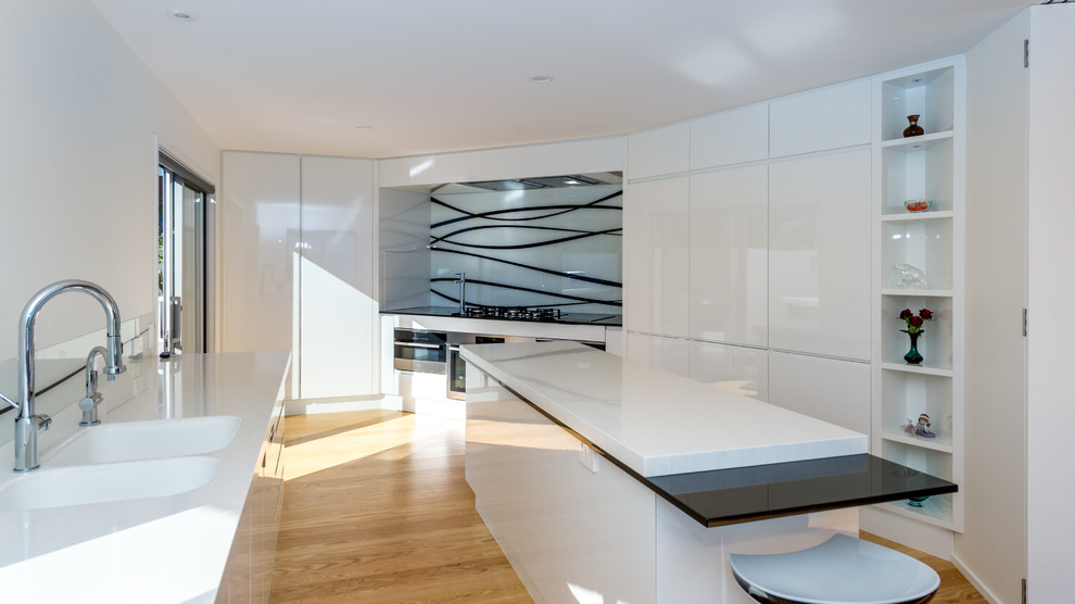 Example of a mid-sized minimalist light wood floor kitchen design in Other with an island