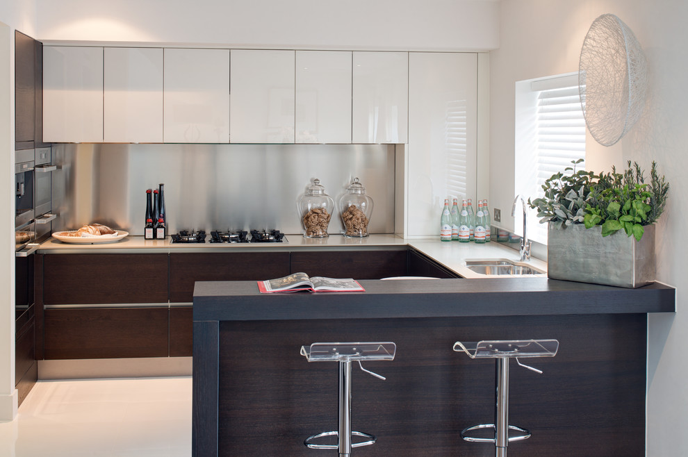 Design ideas for a contemporary kitchen in Surrey with a double-bowl sink, flat-panel cabinets, white cabinets, metallic splashback, stainless steel appliances and a breakfast bar.