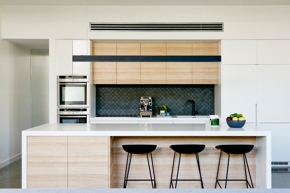 Immagine di una cucina design con lavello sottopiano, ante lisce, ante in legno chiaro, paraspruzzi grigio, elettrodomestici in acciaio inossidabile e pavimento grigio