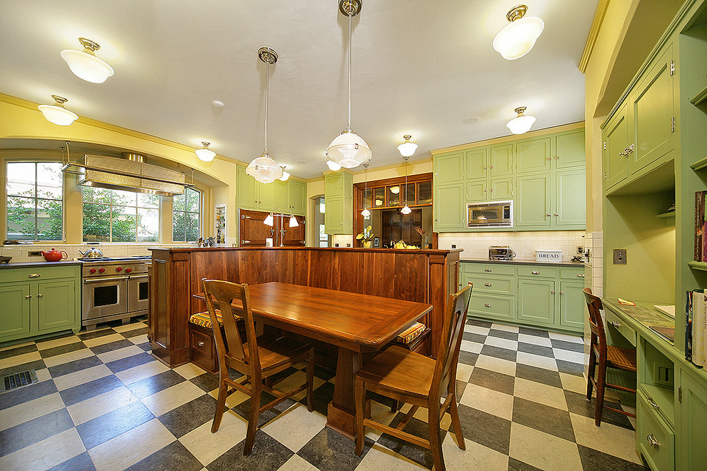 Klassisk inredning av ett kök och matrum, med rostfria vitvaror, luckor med infälld panel, gröna skåp och flerfärgat golv