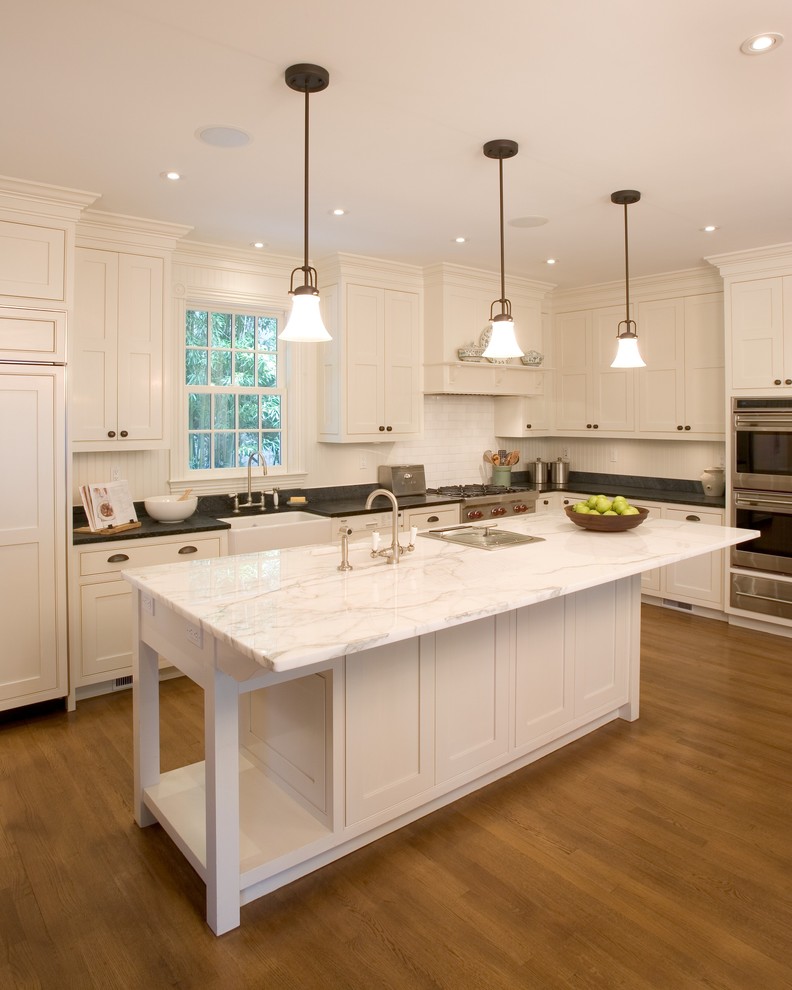 Klassische Küche in L-Form mit Marmor-Arbeitsplatte, Landhausspüle, weißen Schränken und Küchengeräten aus Edelstahl in New York