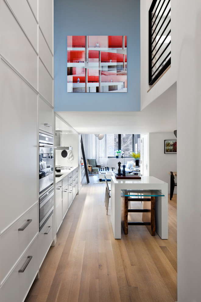 Einzeilige Moderne Wohnküche mit Unterbauwaschbecken, flächenbündigen Schrankfronten und weißen Schränken in New York