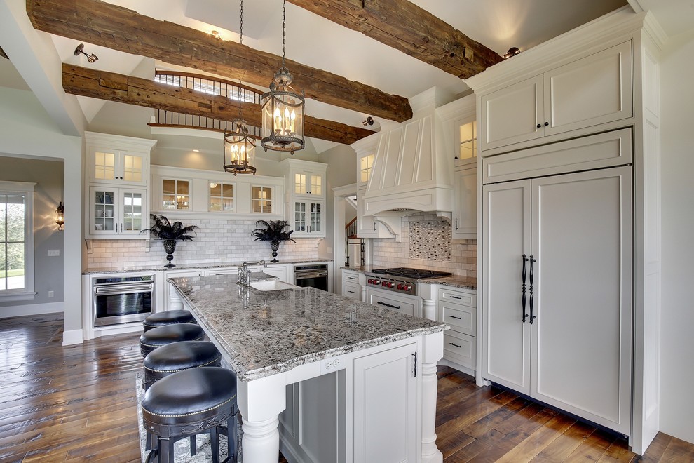 Example of a large classic l-shaped dark wood floor open concept kitchen design in Minneapolis with a farmhouse sink, white cabinets, an island, recessed-panel cabinets, white backsplash, paneled appliances and limestone backsplash