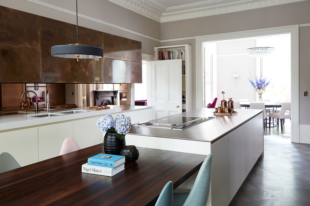 Large contemporary single-wall kitchen/diner in London with flat-panel cabinets, white cabinets, mirror splashback, an island, grey floors, a double-bowl sink and white worktops.