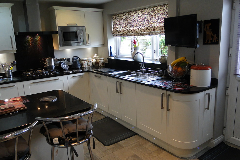 Medium sized classic l-shaped enclosed kitchen in Other with a double-bowl sink, shaker cabinets, yellow cabinets, quartz worktops, black splashback, glass sheet splashback, stainless steel appliances, porcelain flooring, an island and grey floors.