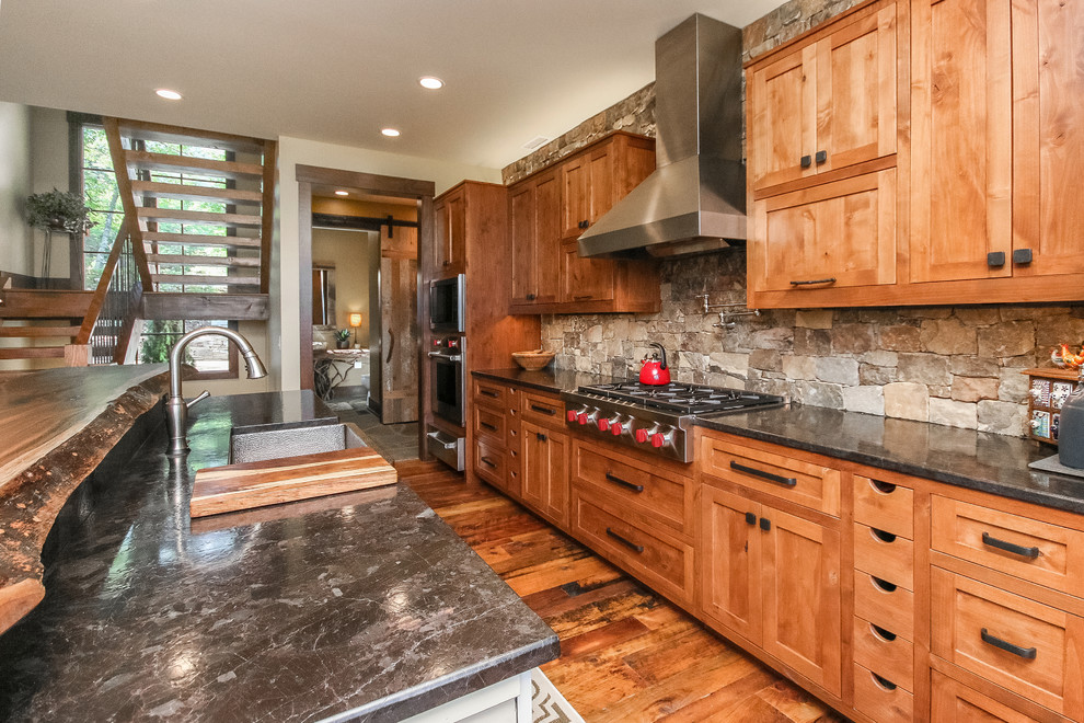 Example of a mid-sized arts and crafts galley medium tone wood floor eat-in kitchen design in Other with shaker cabinets, medium tone wood cabinets, granite countertops, beige backsplash, stone tile backsplash, stainless steel appliances and an island