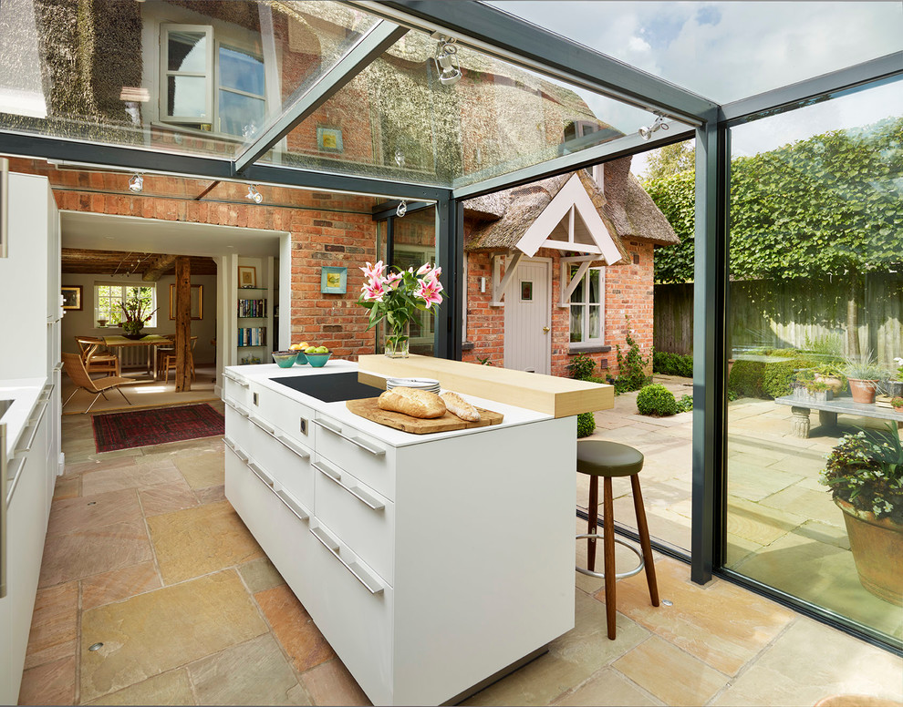 Example of a trendy single-wall kitchen design in Manchester with flat-panel cabinets, white cabinets and an island