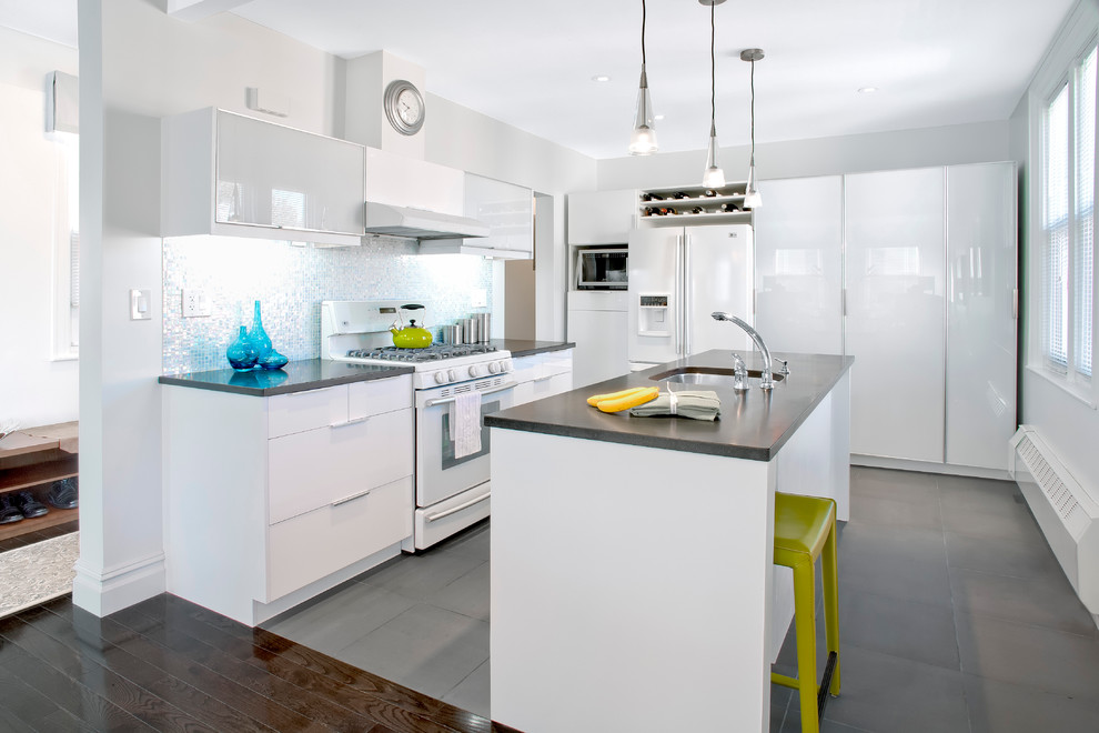 Trendy gray floor kitchen photo in New York with mosaic tile backsplash, white appliances, a single-bowl sink, flat-panel cabinets, white cabinets, metallic backsplash and granite countertops