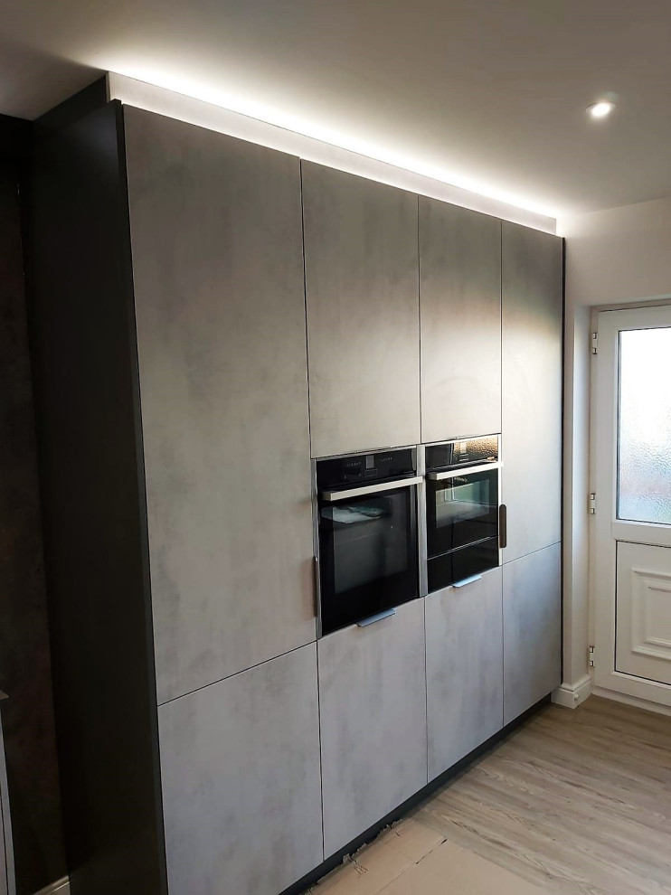 Small industrial galley enclosed kitchen in Other with flat-panel cabinets, distressed cabinets, laminate countertops, grey splashback, black appliances, no island and grey worktops.